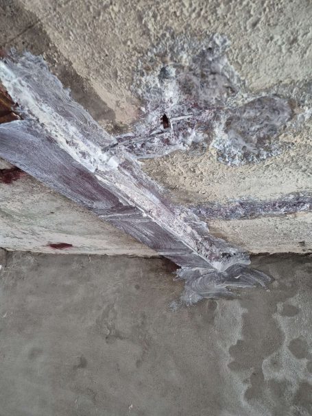 Rissige Wand mit abblätterndem Putz und sichtbaren strukturellen Schäden.